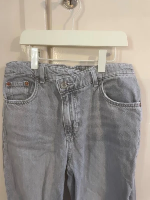 Ljusblå mom jeans från ZARA - Säljer ett par ljus grå mom jeans från ZARA med klassisk femficksdesign och hög midja. Jeansen har raka ben och är gjorda i mjuk denim. Perfekta för en trendig look.