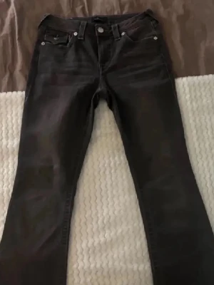 Grå True Religion FLAP - Gråa bootcut True Religion jeans, endast använda 3ggr. Modellen BECCA FLAP. Sitter super bra på mig som är 165-166 i längden, Skriv vid fundering❣️