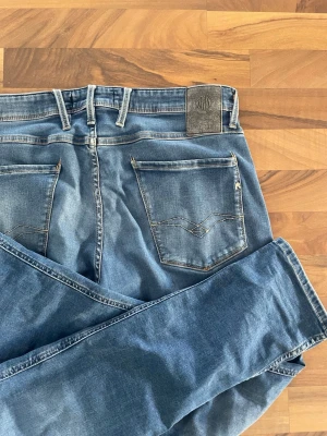 Replay jeans - Snygga och stilrena jeans från Replay, modell Anbass, i en fräsch ljusblå färg. En populär modell känd för sin moderna passform och bekväma stretch. Perfekta för både vardag och mer uppklädda tillfällen. 	•	Storlek: W34 L32 	•	Modell: Anbass 	•	Färg: Ljusblå 	•	Skick: Mycket bra  Detaljer: ✔️ Tillverkade i kvalitativ stretchdenim ✔️ Bekväm och modern passform ✔️ Tidlös design som funkar året runt  Mått (se bild): A: 45cm B: 78cm C: 102 cm D: 17 cm  Hör gärna av dig om du vill ha fler bilder!