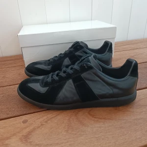 Maison Margiela gats  - Säljer dessa svarta Maison Margiela sneakers | Storlek 41 EU/IT men passar något lite större | Använda men fortrarande i bra skick. | Lite smutsiga på sulan och innersulan men går troligen att tvätta | Nypris: 6000-7000 kr | Priset går att diskutera.
