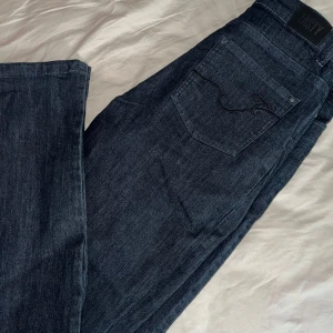Mörkblå jeans - Säljer ett par snygga mörkblå jeans. De har en klassisk femficksdesign och är perfekta för både vardag och fest. Jeansen är i bra skick och har en stilren look.