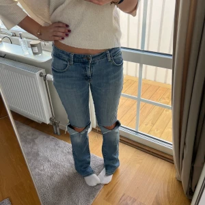 Lågmidjade jeans - Säljer jättefina lågmidjade jeans då de inte kommer till användning. Hål på knäna och slits vid foten på insidan. 💙innerbenslängd: ca 80 centimeter. Midjemått rakt över: 39 centimeter 