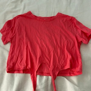 Röd croppad topp från NEU - Säljer en snygg rosa croppad topp från Lager 157. Den är kortärmad och har en knytning framtill. 