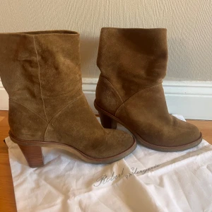 Bruna mocka boots med klack - Säljer ett par snygga bruna boots i mocka från Robert Clergerie. De har en bekväm klack och är perfekta för höst och vinter. Skorna är i bra skick och passar både till vardags och fest.