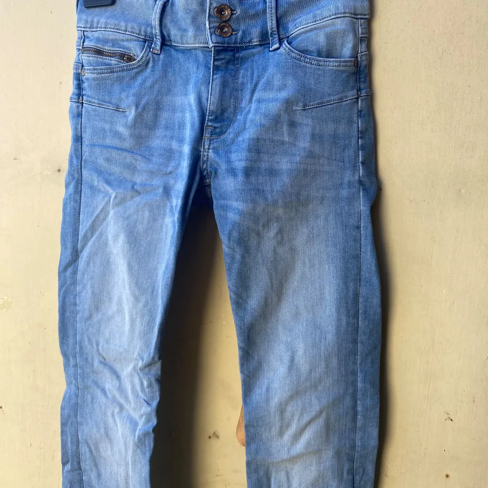Säljer ett par snygga blå jeans från Lindex i storlek 38. De har en klassisk femficksdesign och knappar framtill. Perfekta för vardagsbruk och kan matchas med nästan vad som helst. De är i bra skick och redo för en ny ägare!. Farkut & Housut.