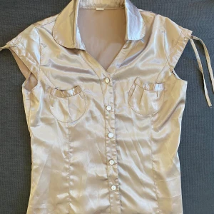 Vintage blouse  - Blus skjorta i fint blankt material som påminner om satin. Färgen är brun beige. Storlek 40 hänvisad på tröjaan men mindre i storlek, mer 38/36.