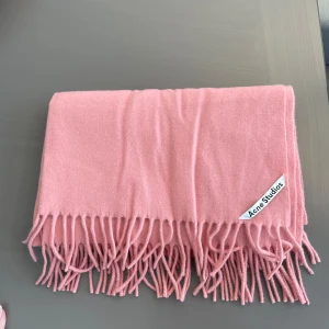 Acne halsduk  - Säljer nu min stora och gosiga Acne halsduk då jag vill köpa en ny. Den är korall rosa och köpt på Åhléns för 2 år sedan. Sparsamt använd så den är i nyskick samt inga fläckar.