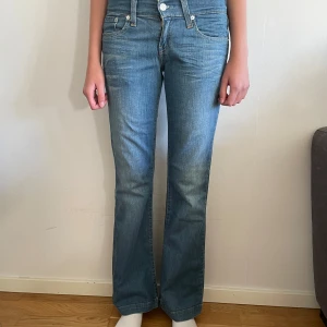 Blå bootcut jeans - Säljer ett par snygga blå bootcut jeans i klassisk stil. De har en låg midja och är i bra skick. 37 cm rakt över midjan och 77 cm i innerbenssöm.