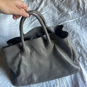 Handväska  - Grå handväska i äkta skinn. Väldigt fint skick, som ny! Så fin nu till hösten💗Nypris 4200 kr
