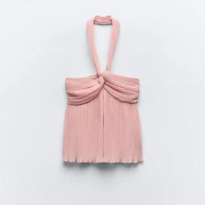 Rosa halterneck topp - Säljer den poplulära rosa halterneck toppen, helt ny med prislappen kvar. Toppen har en elegant knutdetalj framtill och är perfekt för sommarens fester. Den är ärmlös och har en luftig passform som gör den bekväm att bära hela dagen. 