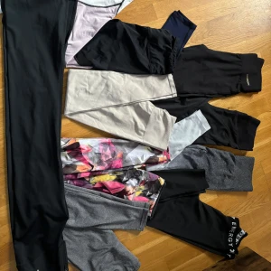 Samling av olika leggings - Säljer en samling av olika leggings i flera färger och mönster. Det finns svarta, gråa och flerfärgade leggings med blommigt mönster. Perfekta för träning eller vardagsbruk. 