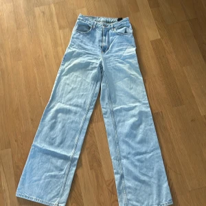Ljusblå jeans med vida ben - Säljer ett par ljusblå jeans med vida ben och hög midja. De har klassisk femficksdesign och stängs med dragkedja och knapp. Perfekta för en avslappnad stil.