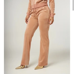 Beige juicy Couture byxor - Snygga beige juicybyxor med rak passform och hög midja. Byxorna har snörning i midjan och praktiska fickor både fram och bak. Perfekta för en avslappnad och stilren look. Bra skick!