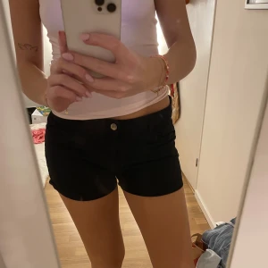 Svarta shorts - Snygga svarta shorts med knappdetalj framtill. Kommer inte till andvändning