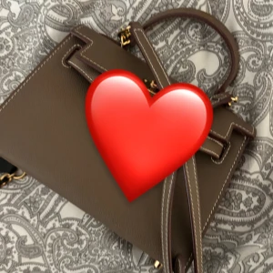 Brun handväska med gulddetaljer - Elegant brun handväska i skinn med stilrena gulddetaljer. Väskan har en praktisk axelrem och ett handtag för olika bäralternativ. Perfekt för att ge en sofistikerad touch till din outfit.