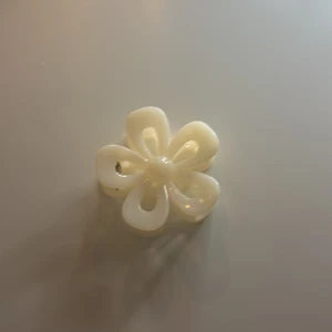 Vit hårklämma i form av en blomma - Snygg och stilren vit hårklämma formad som en blomma. Perfekt för att hålla håret på plats med en touch av elegans. Klämman är lätt och enkel att använda, vilket gör den till ett praktiskt tillbehör för alla tillfällen.