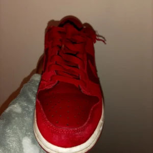 Röda Nike sneakers - Snygga röda Nike sneakers med snörning och vit sula. Perfekta för en sportig look. Skorna har en klassisk design med Nike-logga på sidan.