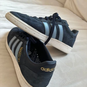 Adidas Spezial sneakers DIF stl 40 1/2  - Snygga Adidas Spezial sneakers i mörkblå mocka med ljusblå ränder och guld detalj. Perfekta för en stilren look med klassisk snörning och bekväm passform. 