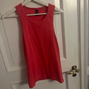 Rosa/röd linnetopp från SOC - Snygg rosa/röd linnetopp från SOC i storlek L. Perfekt för varma sommardagar eller träning. Enkel och stilren design med rund halsringning.