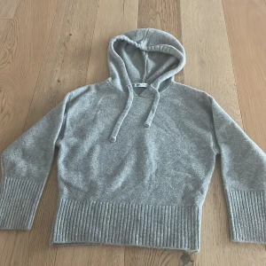 Grå hoodie från Zara - Mysig grå hoodie från Zara i mjukt material. Tröjan har en klassisk huva med dragsko och ribbade muddar vid ärmslut och nederkant. 