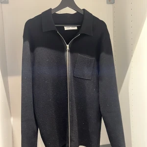 Svart och grå tröja från Samsøe Samsøe - Snygg svart och grå tröja från Samsøe Samsøe med dragkedja och krage. Tröjan har en bröstficka och långa ärmar, perfekt för en stilren look. Storlek XL men passar L