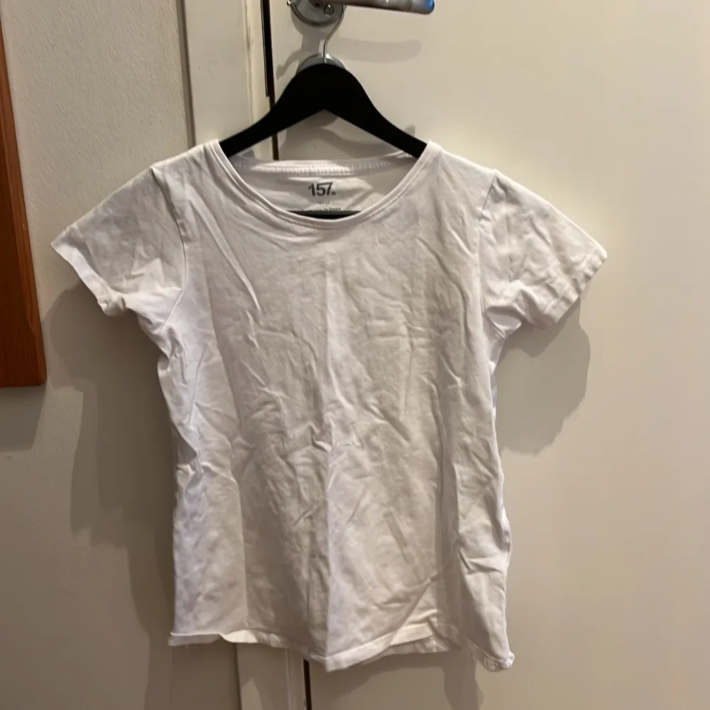 Klassisk vit t-shirt från 157 i bomull. Perfekt basplagg med rund hals och korta ärmar.. T-paidat.