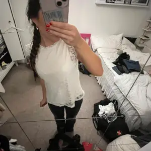Säljer en elegant vit blus med spetsdetaljer och korta ärmar. Perfekt för en stilren look. Blusen har en vacker spetsdesign och en bekväm passform.