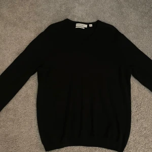 Svart tröja från Calvin Klein - Säljer en stilren svart tröja från Calvin Klein i extra fin merinoull. Tröjan har en klassisk v-ringning och långa ärmar, perfekt för en elegant look.