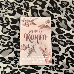My Dark Romeo - Boken 'My Dark Romeo' av Parker S. Huntington och L.J. Shen har ett omslag med klassiska änglamotiv i mjuka färger. Titeln är i en elegant, stor stil. Baksidan antyder en dramatisk och mörk berättelse om kärlek och intriger.
