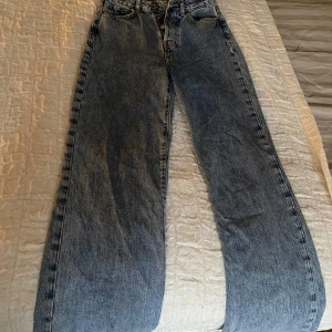 Blå jeans med hög midja - Säljer ett par klassiska blå jeans med hög midja och något vida ben. De har en knappgylf och femficksdesign. Älskar dessa jeans, dom sitter som en smäck och är skitsnygga på! Passar 32/34, och en lång person, jag är 163 och får vika upp ändarna 1 decimeter. Jeansen har en fläck, tycker inte att det syns på särskilt mycket.