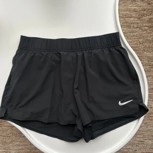 Nike shorts  - Säljer ett par korta Nike Shorts som är lite lösare passform med inbyggda tajta shorts under. Finns fickor på båda sidorna så perfekt att ha på tex paddel eller tennisbanan. Fint skick!🤩