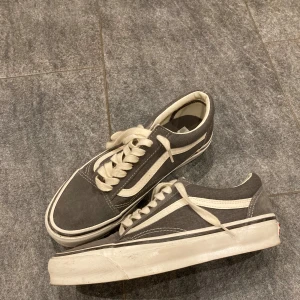 Grå sneakers från Vans - Snygga grå sneakers från Vans med klassisk vit sula och snörning. Perfekta för en avslappnad stil.
