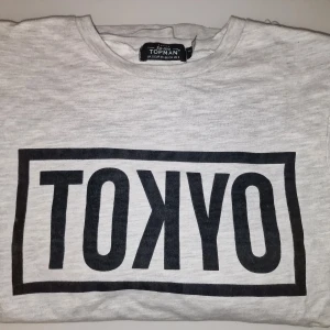 Grå långärmad tröja från Topman - Säljer en långärmad tröja från Topman med texten 'TOKYO' i svart på framsidan. Perfekt för en casual look! Garderobsrensning så kika gärna på övriga auktioner.