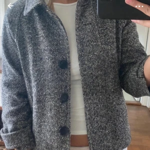 Grå trekvart ärmad kappa - Snygg grå trekvarts ärmad kappa med svarta knappar. Perfekt för höst och vår. 