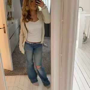 Blå jeans med hål i - Snygga blå jeans med slitningar på knäna. De har en avslappnad passform och är perfekta för en casual look. Kombinera med en enkel topp för en stilren outfit. garna är från Lindex har gjort egna hål. Skriv om ni vill ha mer bilder och de som jag har lagt ut är mina bilder.