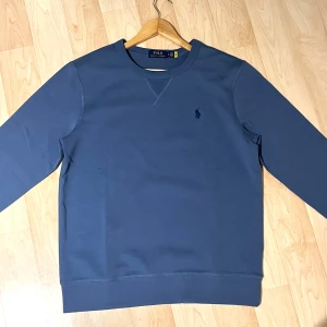 Polo Ralph Lauren Sweatshirt - Säljer en stilren blå sweatshirt från Ralph Lauren. Helt ny har inte använt den, då den är lite stor på mig. Skriv gärna vid funderingar!🤩