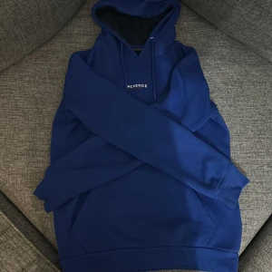 Blå hoodie från McKenzie - Snygg blå hoodie från McKenzie med justerbar huva och känguruficka. Perfekt för en avslappnad stil. Märkeslogga på bröstet ger en stilren touch.