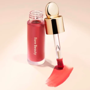 Flytande rouge från Rare Beauty - Flytande rouge från Rare Beauty i en vacker röd nyans. Kommer i en elegant flaska med en guldig applikator. Perfekt för att ge kinderna en naturlig och fräsch färg. Bara testad på handen.