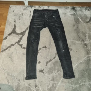 Svarta Dsquared2 jeans - Snygga svarta jeans från Dsquared2 med en cool, sliten look. De har en knappgylf och klassisk femficksdesign. Perfekta för en trendig stil. Det finns några jätte små skador i insidan men de syns eller känns inte.
