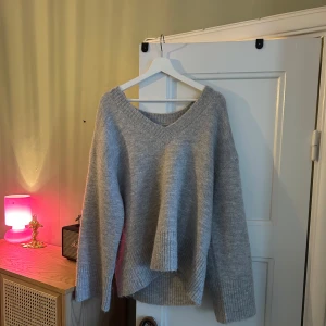 Grå stickad tröja från Gina Tricot - Mysig grå stickad tröja från Gina Tricot med v-ringning och ribbade detaljer vid ärmslut och nederkant. Strl M, Premium Quality.