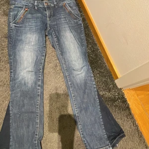 Blå egensydda bootcut jeans från espirit - Snygga blå bootcut jeans som jag sytt om själv från Espitit med klassisk femficksdesign och dragkedja. Perfekta för en avslappnad stil med en touch av retro. De har en lätt tvättad look som ger dem en cool vibe.