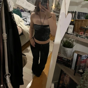 Svart tubtopp med mönster - Snygg svart tubtopp med ett unikt mönster i grått. Toppen har en snörning i ryggen och är perfekt för en stilren look. Passar bra till både jeans och kjol. Supersöta pärlor och spännbar vid bysten, knappt använd💗