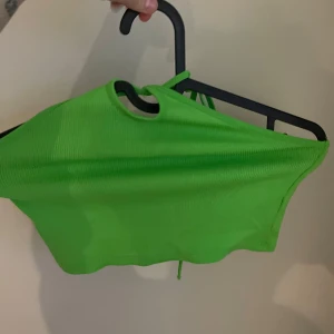 Grön ribbad topp med knytning från Zara - Säljer en snygg grön ribbad topp med knyting från Zara. Toppen har en enkel design med knyt hals och är perfekt för en trendig look. Passar bra till både jeans och kjol.