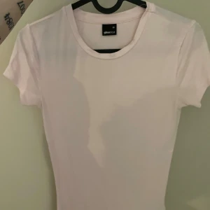 ljus rosa t-shirt från Gina Tricot - Säljer en klassisk ljus rosa t-shirt från Gina Tricot i storlek XS. Den har en rund halsringning och korta ärmar, perfekt för en enkel och stilren look. Passar till alla tillfällen och är ett måste i garderoben. 
