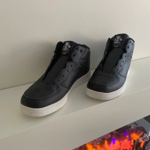 Svarta sneakers från Townz - Snygga svarta sneakers från Townz med en stilren design. Skorna har en vit sula och är tillverkade i syntetmaterial. Perfekta för en casual look. Skosnören följs med! Kan tänka mig att gå ner i pris vid snabb affär!! 