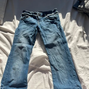 Blå jeansbyxor - Snygga blå jeansbyxor med klassisk femficksdesign och knappgylf. Perfekta för en avslappnad stil. De har en rak passform och är tillverkade i slitstarkt denim.
