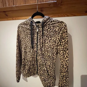 Velour hoodie  - Säljer en leopardmönstrad hoodie med dragkedja och svarta snören. Super mjuk och skön, sparsamt använd. 