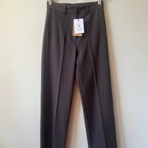  kostymbyxor - Snygga grå kostymbyxor med en klassisk design. De har en rak passform och är perfekta för en stilren look. Byxorna har hällor för bälte och en diskret dragkedja framtill.