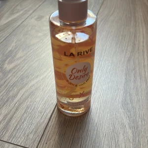 La Rive Only Desire Body & Hair Mist - Fräsch och uppfriskande body & hair mist från La Rive. Flaskan är genomskinlig med en ljusrosa vätska och har en vit kork. Perfekt för att ge en lätt doft till både kropp och hår.