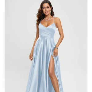 Ljusblå långklänning med slits - Elegant ljusblå långklänning i satin med smala axelband och en vacker omlottdesign. Klänningen har en djup slits och en öppen rygg med snörning som ger en sofistikerad look. Använd 1 gång. Nypris: 2000kr med frakt.